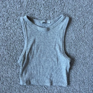 Grå ribbad linnetopp från Zara - Säljer en ljusgrå ribbad linnetopp från Zara. Toppen är ärmlös och croppad med rund halsringning. Inga täcken på användning🥰🥰