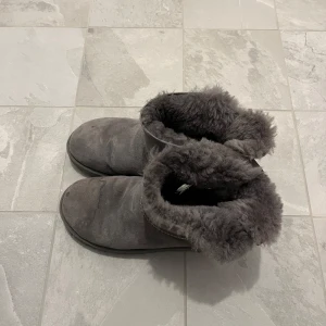 Gråa boots med foder - Mysiga grå boots med fluffigt foder och rund tå. Perfekta för kyliga dagar och håller fötterna varma. Klassisk design med platt sula och mjukt material både in- och utvändigt.
