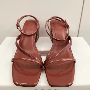 Bruna sandaler med klack - Säljer ett par stilrena bruna sandaler från Bershka med fyrkantig tå och bred klack. Skorna har tunna remmar och en glansig finish som ger en modern look. Perfekta för dig som vill ha något trendigt och bekvämt. Har  används 1 gång. Priset kan diskuteras.  