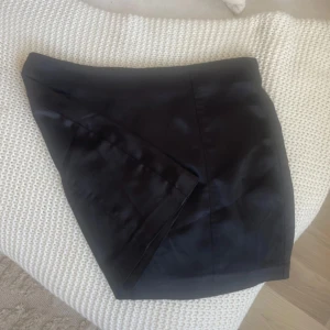 Svart minikjol ginatricot - Säljer en svart minikjol med enkel och stilren design. Kjolen har en rak passform och är perfekt för dig som gillar en klassisk look. Passar till många olika outfits och är lätt att matcha med olika toppar.