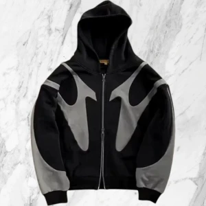 Svart hoodie med gråa detaljer - Säljer en svart hoodie med dragkedja och stora gråa mönster på ärmar och framsida. Jackan har huva och ribbade muddar. Perfekt för dig som gillar streetwear och vill sticka ut med en unik design.