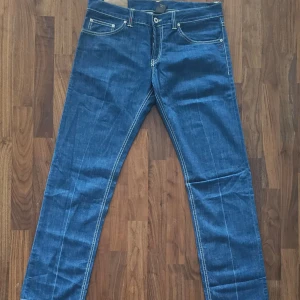 Dondup jeans - slim fit - W34  - Snygga blå jeansbyxor från Dondup, tillverkade i Italien. Klassisk femficksmodell med kontrastsömmar och raka ben. Tillverkade i 100% bomull för en skön känsla. Perfekta för dig som gillar stilrena och tidlösa jeans.