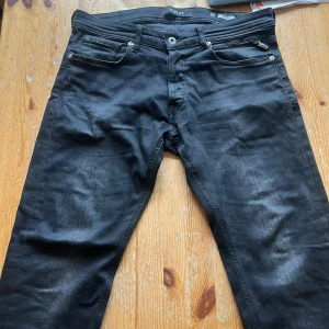 Svarta jeans från Replay - Säljer ett par svarta Replay jeans med klassisk femficksdesign och diskreta slitningar. Byxorna har dragkedjegylf och passar perfekt till dig som gillar stilrena och snygga jeans med en modern look. Modellen är Grover och är i storlek 31/32! Används några gånger men är i bra skick, nypris 1799kr! Hör av dig vid frågor😊