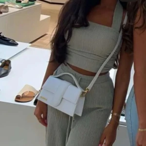 Ljusgrå vida byxor med knytband - Snygga ljusgrå byxor med hög midja och knytband i midjan. Byxorna har en rak och vid passform som ger en avslappnad look. Perfekta att matcha med en crop top eller en enkel t-shirt.