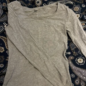 Grå långärmad topp från 157🤍 - Säljer en basic grå långärmad topp från 157. Tröjan har rund halsringning och är tillverkad i mjuk bomullsblandning med lite stretch. Perfekt att styla med jeans eller kjol. Figursydd🩷