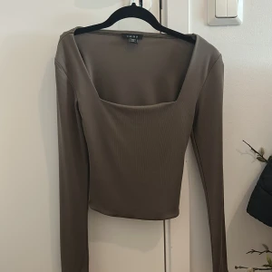 Brun ribbad långärmad topp från Amisu - Säljer en brun långärmad topp från Amisu med fyrkantig ringning och ribbad struktur. Toppen är croppad och har en tight passform, perfekt att styla till olika outfits. Helt oanvänd.