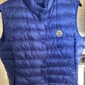 Blå dunväst från Moncler - Snygg blå väst från moncler. Storlek 5 den är för liten för mig och knappt använd. Köpt i Göteborg från kicksnstuff. Har kvitto som jag kan skicka privat om ni skulle önska de. Pris 3800. Kan tänka mig gå ner till 3500 om de behövs!