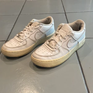 Nike Air Force 1 vita sneakers - Klassiska vita Nike Air Force 1. Skicket utanpå är väldigt bra. Dock finns det en deffekt i hälen på insidan i båda skorna som visas i bilderna. Sulorna är även gulnade. Pris går att diskutera vid snabb affär!