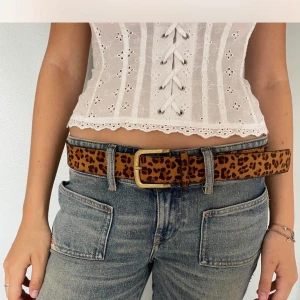 Leopardmönstrat bälte med guldfärgat spänne - Chic och coolt bälte med leopardmönster och ett stort guldfärgat spänne. Bältet är i klassisk modell och passar perfekt till jeans eller kjol. 