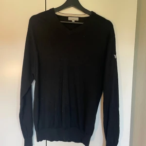 Svart v-ringad tröja från Lyle & Scott - Rensade ut lite i garderoben o hittade denna tröjan. Det är en svart v-ringad tröja från Lyle & Scott med broderad logga på armen. Tröjan är i jätte fint skick utan synliga defekter. Hör av er om ni har frågor.
