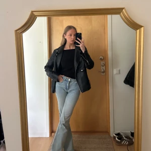 Svart skinnjacka med dragkedjor - Säljer en svart skinnjacka med silvriga dragkedjor och detaljer. Jackan har klassisk bikerstil med bred krage och fickor framtill. Perfekt för dig som vill ha en cool och tidlös look.