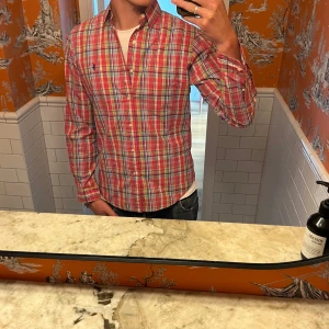 Rutig skjorta från Polo Ralph Lauren - Säljer en klassisk rutig skjorta från Polo Ralph Lauren i rött, blått och vitt. Skjortan har lång ärm, knappar framtill och en liten broderad logga på bröstet. Perfekt för dig som gillar en tidlös och stilren look. Perfekt inför sommaren!!