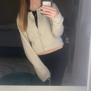 kofta - Säljer en beige croppad kofta med långa ärmar och knappar framtill. Perfekt att slänga över en topp för en chill och snygg look. Supermjuk och enkel att matcha med det mesta!