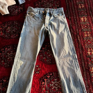 Ljusblå jeans från HOPE, Modell Rush - Säljer ett par klassiska ljusblå jeans från HOPE med raka ben/Bootcut och knappgylf. Jeansen har fem fickor och tydliga sömmar. Perfekta för dig som gillar en tidlös och avslappnad stil. Modell Rush, Bra skick