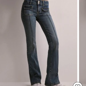 Blå bootcut jeans med fickdetaljer - Snygga blå bootcut jeans med markerade sömmar och dubbla fickor framtill. Jeansen har låg midja och klassisk femficksdesign. Aldrig använda 