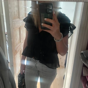 Svart blus med volangärmar - Svart snygg blus med korta volangärmar och v-ringning