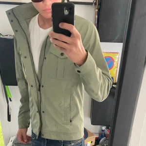 Grön jacka från J.Lindeberg - Snygg grön jacka från J.Lindeberg med dragkedja och knappar framtill. Jackan har långa ärmar och två bröstfickor med knappar. Perfekt för vår och höst 🍂 Skriv för mer info ℹ️, bilder eller funderingar🤩