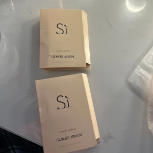 Sì Eau de Parfum från Giorgio Armani - Säljer två små provflaskor av Sì Eau de Parfum från Giorgio Armani. Parfymen kommer i eleganta ljusbeige kartonger med svart text och innehåller en liten flaska med spray. Perfekt för att testa doften eller ha med i väskan, 2ml. 