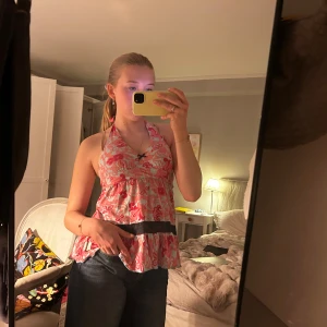 Odd Molly topp - Säljer en söt rosa halterneck blus med blommigt mönster och svart band i midjan. Toppen knyts i nacken och har en luftig, volangig passform. Perfekt för varma dagar.💗💗