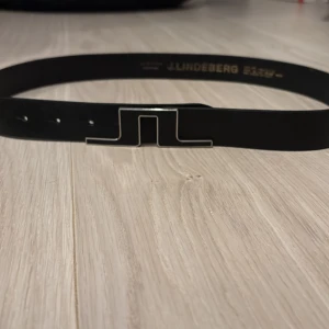 Svart bälte från J.Lindeberg  - Säljer mitt J.lindberg bälte för använder inte skriv om intresse har använt 3 gånger. Den är i bra skick.