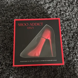 Shoo Addict Envy parfym i klackformad flaska - Parfymen Shoo Addict Envy från Laurélle London kommer i en unik, röd klackformad flaska. Förpackningen är svart och röd med elegant design. Flaskan rymmer 100 ml Eau de Parfum och är en snygg detalj på parfymhyllan.