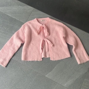 Ljusrosa stickad kofta från Gina Tricot - Superfin ljusrosa stickad kofta från Gina Tricot med två söta rosetter framtill. Aldrig använd, därav inga defekter. Skriv vid frågor🩷🩷