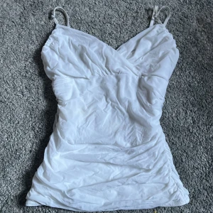 Vit omlottklänning med smala axelband från H&M - Säljer en vit figursydd topp från hm