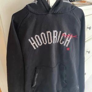 Svart hoodie från Hoodrich med broderad text - Svart hoodie från Hoodrich i storlek L. Tröjan har broderad logga och text på bröstet, pris kan diskuteras och skriv gärna vid fundering. Ny pris runt 1000kr och knappt använd.
