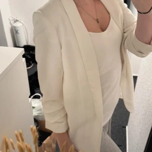 Vit kavaj från Pieces - Säljer en stilren vit kavaj från Pieces. Kavajen har en klassisk passform med långa ärmar och enkel, öppen front utan knappar. Perfekt att slänga över en topp för en clean look. Tunnare material som känns lätt och smidigt.