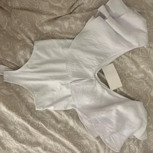 Vit body med volang  - Vit body från Zara. Den är helt ny med prislapp kvar, den är i storlek M men passar mig som vanligtvis har storlek s. 