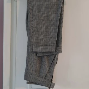 Gråa snygga kostymbyxor från H&M! - Snygga grå kostymbyxor med klassiskt rutigt mönster med dragkedja och spänna i midjans sida. Stiliga, unika och mycket bekväma! 