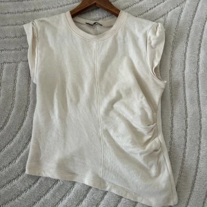 Vit ärmlös topp från Zara - Säljer en enkel och stilren vit ärmlös topp från Zara. Perfekt för sommardagar eller som ett basplagg i garderoben. Toppen är i bra skick och har en mjuk och bekväm passform.