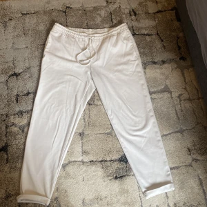 Vita mjukisbyxor med snörning - Säljer ett par vita mjukisbyxor med resår och snörning i midjan. Byxorna har raka ben och fickor bak. Perfekta för en avslappnad stil och riktigt sköna att ha på sig.
