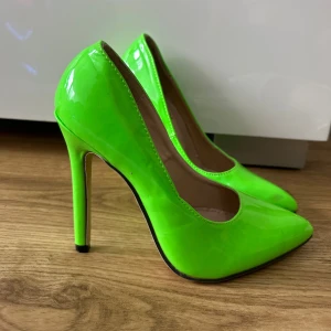 Neongröna pumps med klack - Säljer ett par riktigt snygga neongröna pumps med hög klack och spetsig tå. Skorna har en glansig finish och är perfekta för dig som vill sticka ut. Passar till dig som gillar färg och trendiga detaljer.  De är helt oanvända i storlek 36