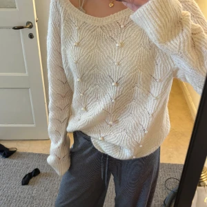 Vit stickad tröja med pärlor från LOFT - Säljer en vit stickad tröja från LOFT med dekorativa pärlor framtill. Tröjan har ett diskret mönster, rund halsringning och långa ärmar. Perfekt för lager-på-lager och ger en elegant touch till din outfit.