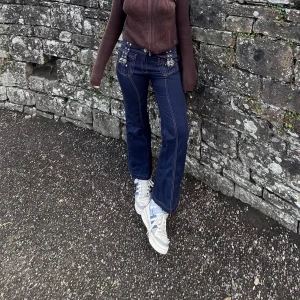 Low waist Mörkblå byxor med bältesdetaljer - Coola mörkblå byxor med vita sömmar och bältesdetaljer. Low waist, raka ben/utsvängda, slutar vid ankeln på mig som är 165cm. Köpta second hand i England! 