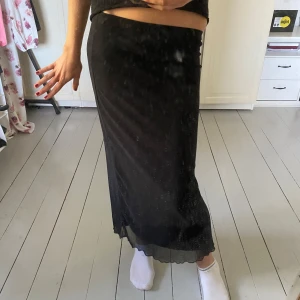 Svart långkjol i mesh - Säljer en svart långkjol i mesh med lätt transparent känsla. Kjolen har rak passform och resår i midjan för extra komfort. Perfekt att styla med en crop top eller stickad tröja.