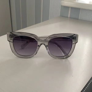 Grå transparenta solglasögon från Chimi - Snygga solglasögon från Chimi med transparent grå båge och mörka tintade glas. Rektangulär form med breda skalmar för en trendig look. Perfekt accessoar för att lyfta din stil. Några defekter som syns på sista bilden☺️Modell 08 grey. Kom med prisförslag om priset ej passar! 