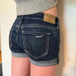 Mörkblå jeansshorts från Hollister - Sjukt snygga mörkblå jeansshorts från Hollister. Shortsen har låg midja och slitna detaljer framtill för en trendig look. Perfekta för varma dagar och enkel att matcha med olika toppar. Följ gärna mig för kommer ladda upp fler snygga shorts och kjolar! Hör gärna av dig och tryck gärna på köp nu!💞💕