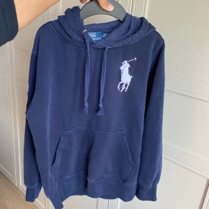 Ralph Lauren hoodie - Säljer en galet snygg marinblå Raffe hoodie perfekt till sommarkvällar | Storlek: På etikett S, men passar XS | Skick: 7/10 skick, tröjan är i hyfsat bra skick förutom väldigt små hål på magen, därav priset | Nypris: 1900kr, vårat är 525kr | Hojta till vid fundering 💭 
