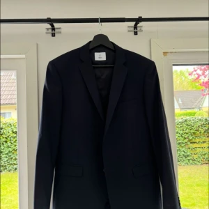 Mörkblå kostym med väst och byxor - Säljer en stilren marinblå kostym från märket Bläck, inköpt på Brothers för 3 500 kr. Endast använd en gång – i nyskick!  Storlekar:  • Kavaj: 50  • Byxor: 50  • Västen: 48  Kostymen har en modern passform och passar perfekt till både bröllop, student, eller andra festliga tillfällen. Säljes endast som set.  Nypris: 3 500 kr Mitt pris 1300  Kom med bud