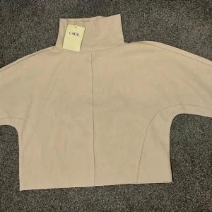 Beige polotröja  - Oanvänd stilren beige polotröja. Tröjan har hög krage och långa ärmar, perfekt för lager-på-lager. Enkel och clean design som passar till mycket. Materialet känns mjukt och bekvämt🤎👕