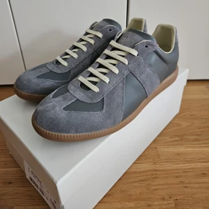 Masion Margiela GATS  - Nu säljer jag ett par stilrena gråa GATS i storlek 43, skicket är 9/10, boxen och dustbags ingår, skriv vid minsta lilla och lägre pris vid snabbaffär.