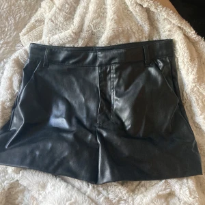 Svarta skinnshorts från Zara - Snygga svarta shorts i skinnimitation från Zara. Perfekta för att lyfta vilken outfit som helst med en edgy touch.