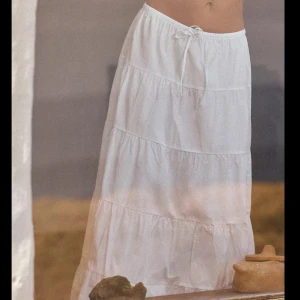 Vit volangkjol från Zara - Säljer en lång, vit kjol från Zara med flera volanglager och resår i midjan. Kjolen har en luftig och flowy känsla, perfekt för varmare dagar. Enkel att matcha med olika toppar för en fräsch look. Oanvänd med prislapp kvar. Nypris 399 säljer för 200. 