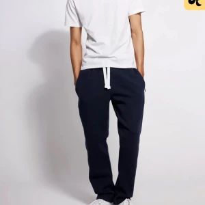 Russemerch mjukisbyxor mörkblå  - Säljer ett par mörkblå mjukisbyxor från russemerch med vit dragsko i midjan. Byxorna har en avslappnad passform och resår i bensluten. Perfekta för chill dagar eller när du vill vara bekväm.