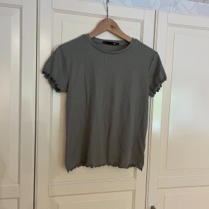 Ribbad t-shirt  - Grön/grå ribbad t-shirt med volangkant.