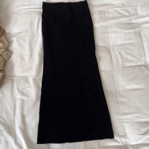 Svart ribbad långkjol Zara - Svart ribbad långkjol från Zara i stretchigt material. Kjolen har en snygg slits framtill och sitter figurnära. 
