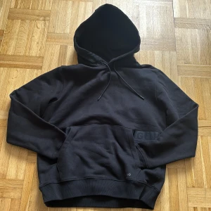 Svart hoodie från HUGO i XS - Svart hoodie från HUGO i storlek XS. Klassisk modell med huva och snörning, samt stor känguruficka framtill. Mjuk och skön bomullsblandning, perfekt för en chill och stilren look.