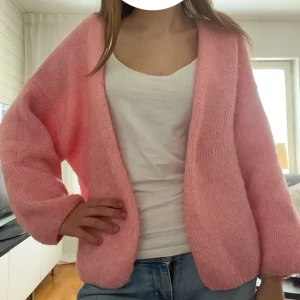 Rosa stickad kofta från Lindex - Säljer den populära ljusrosa stickade koftan från Lindex. Den har en öppen front och lång ärm. Koftan har en fluffig och mjuk känsla, perfekt att slänga på sig över en linne.🥰